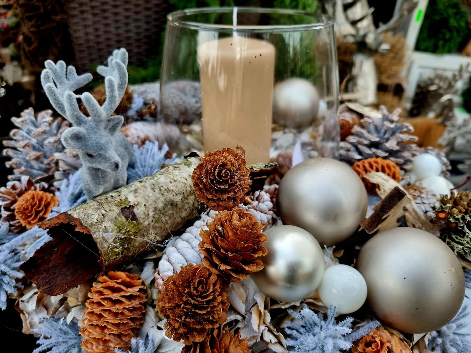 Tischgesteck mit Stumpenkerze im Glas, Zapfen und silbernen Kugeln